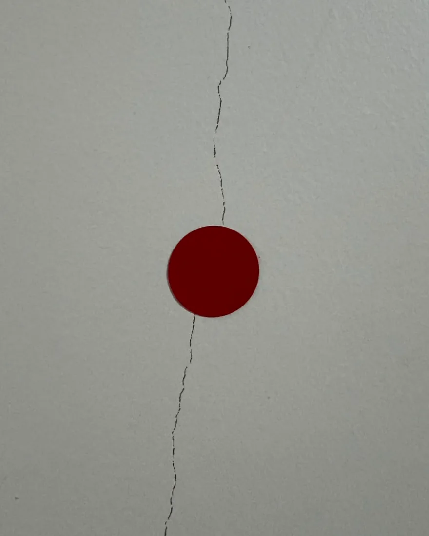 Fissura vertical em parede interna, marcada com adesivo circular vermelho